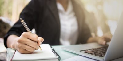 Young asia student study in the public library, She making note on notebook and using laptop